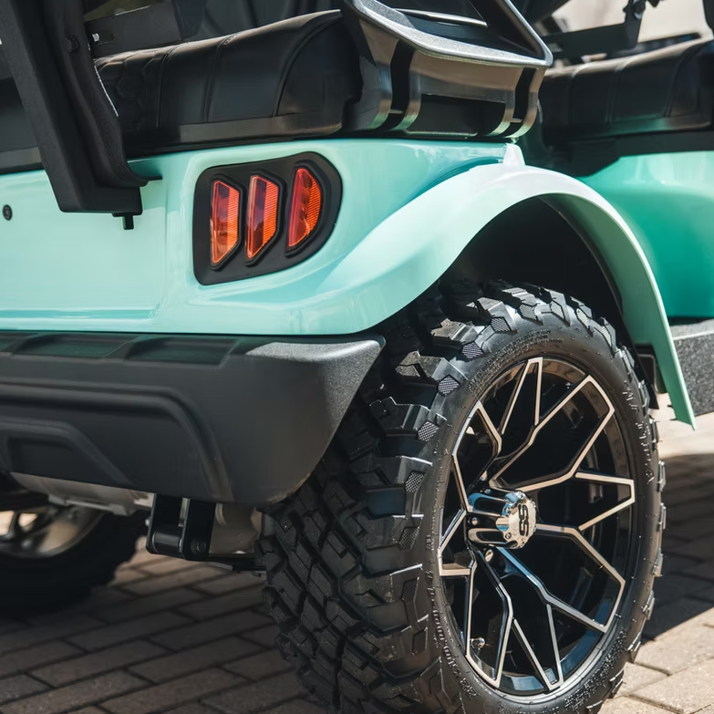 Close-up of a turquoise golf cart with a focus on the rear wheel and tire.